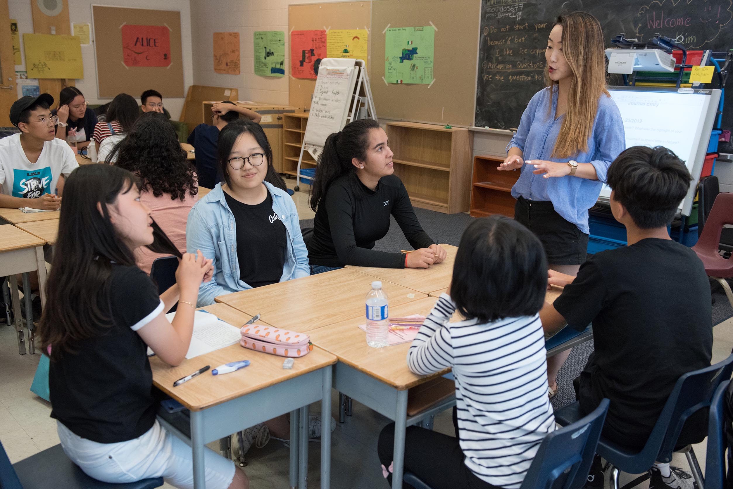 Students sitting at desk talking to the teacher Open Gallery